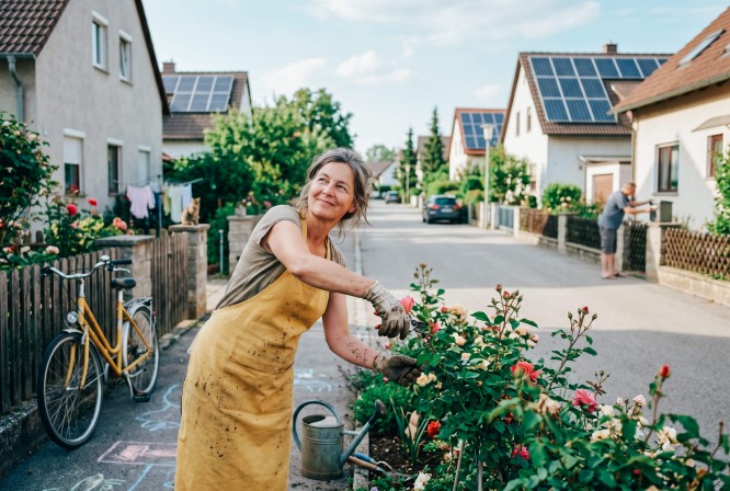 Frau schneidet Rosen vor dem Haus
